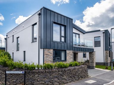 A modern residential building with stone and metal facade at Chapel Rock Close