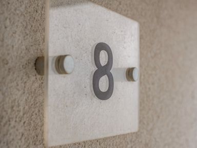 A glass plaque with the number 8 mounted on a textured wall at Beach Haven in Perranporth