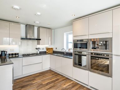 A modern kitchen with white cabinets ovens a gas stove and a window at Beach Haven in Perranporth