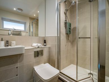 A bathroom with a toilet a sink and a glass shower enclosure at Beach Haven in Perranporth