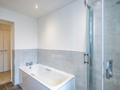A bathroom with a bathtub and a glass shower enclosure at Beach Haven in Perranporth