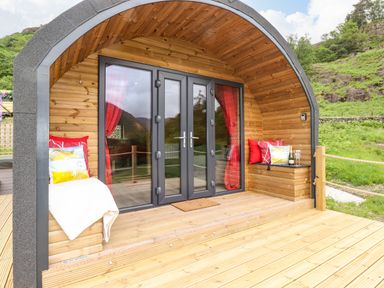 A wooden pod structure with glass doors and red curtains on a wooden deck at Hartsop Magic - Crossgate Luxury Glamping in Hartsop near Glenridding