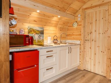 A kitchen with white cabinets red appliances and wooden walls at Hartsop Magic - Crossgate Luxury Glamping in Hartsop near Glenridding