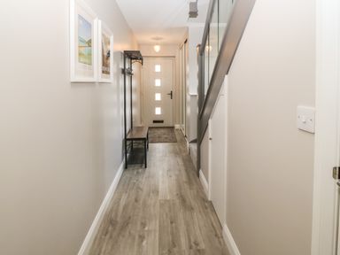 A hallway with a wooden bench coat rack framed pictures and staircase at 1 Crud Y Mor in Barmouth