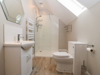 A bathroom with a sink cabinet toilet shower and skylight at 1 Crud Y Mor in Barmouth