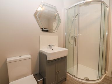A bathroom with a toilet sink cabinet and glass shower at 1 Crud Y Mor in Barmouth