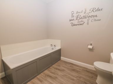 A bathroom with a bathtub toilet and wall decals at 1 Crud Y Mor in Barmouth