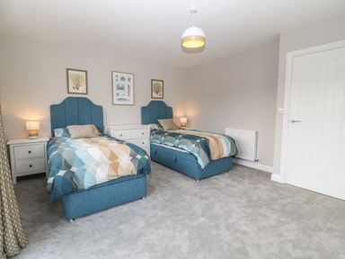 A bedroom with two single beds with blue headboards and patterned bedding at 1 Crud Y Mor in Barmouth
