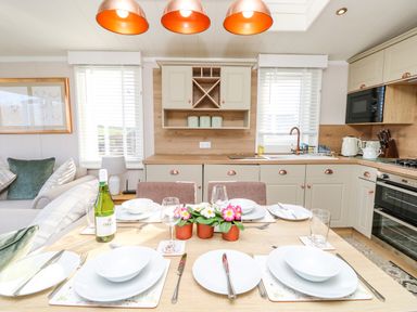 A kitchen and dining area with a table set for four and kitchen cabinets at Vendee Lodge Thorness Bay Holiday Park near Cowes