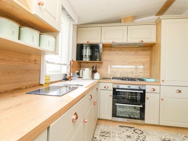A kitchen with counters a stove oven microwave and labeled canisters at Vendee Lodge Thorness Bay Holiday Park near Cowes