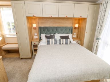A bedroom with a bed and pillows flanked by bedside tables and cabinets at Vendee Lodge Thorness Bay Holiday Park near Cowes