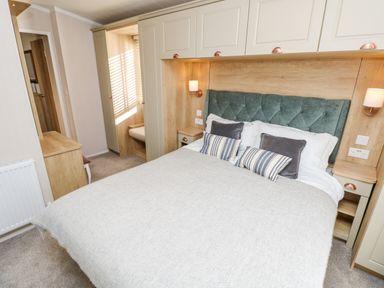 A bedroom with a large bed pillows bedside tables and built in wardrobes at Vendee Lodge Thorness Bay Holiday Park near Cowes