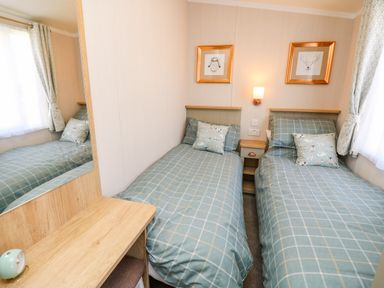 A bedroom with two single beds with checkered bedding and a wooden desk at Vendee Lodge Thorness Bay Holiday Park near Cowes