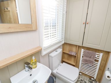 A bathroom with a sink a toilet a towel rail and cabinets at Vendee Lodge Thorness Bay Holiday Park near Cowes