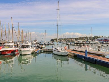 A marina with boats docked along piers and a town in the background at Vendee Lodge Thorness Bay Holiday Park near Cowes
