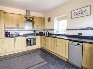A kitchen with wooden cabinets stainless steel appliances and a window at Caerffynon Bach in Dyffryn Ardudwy