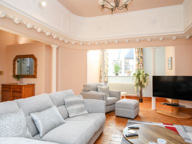 A living room with gray sofas a flat screen TV and wooden furniture at Ty Biwmares in Beaumaris