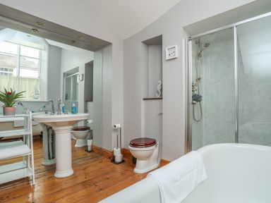 A bathroom with a bathtub a pedestal sink a toilet and a shower enclosure at Ty Biwmares in Beaumaris