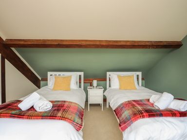 A bedroom with two single beds a nightstand and wooden beams on the ceiling at Ty Biwmares in Beaumaris