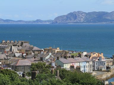 A coastal town with rows of houses near a body of water with hills in the background at Ty Biwmares in Beaumaris