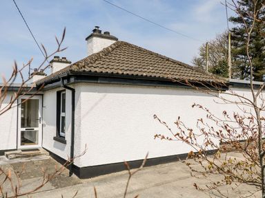 Exterior of a white house with a tiled roof and a glass door at Bridgetown Cottage in Kerrykeel County Donegal