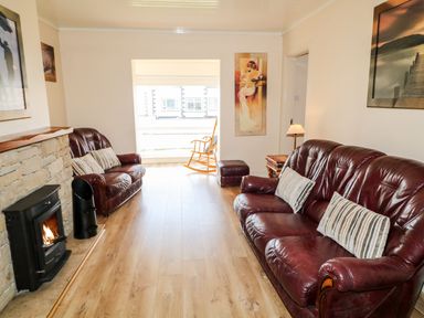 A living room with two leather sofas a wood burning stove and a rocking chair at Bridgetown Cottage in Kerrykeel County Donegal