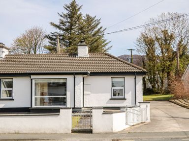 A white single-story house with a tiled roof and a small front garden with a gate at Bridgetown Cottage in Kerrykeel County Donegal