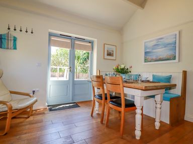 A dining area with a wooden table and chairs by blue double doors at Cameo Atlantic Highway near Bude