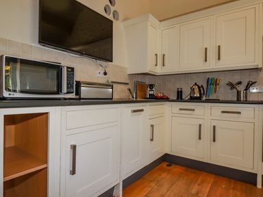 A kitchen with white cabinets microwave toaster television kettle and kitchen utensils at Cameo Atlantic Highway near Bude