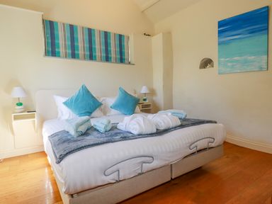 A bedroom with a bed with blue pillows and folded towels at Cameo Atlantic Highway near Bude