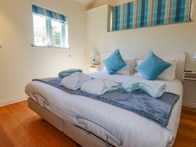 A bedroom with a double bed two blue pillows bathrobes and towels on the bed at Cameo Atlantic Highway near Bude
