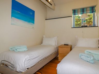 A bedroom with two single beds a wooden nightstand a lamp and a window at Cameo Atlantic Highway near Bude