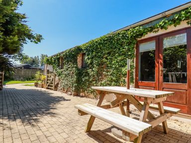 An outdoor patio area with a wooden picnic table next to a building covered in ivy at Cameo Atlantic Highway near Bude