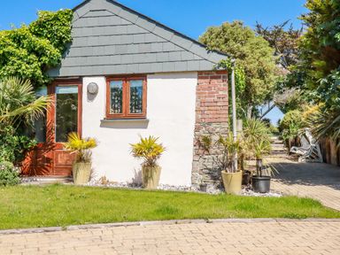 Exterior of a small building with a wooden door and window with plants in pots outside Cameo Atlantic Highway near Bude