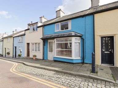A row of terraced houses with different colored facades along a paved street at Penrallt in Cemaes Bay