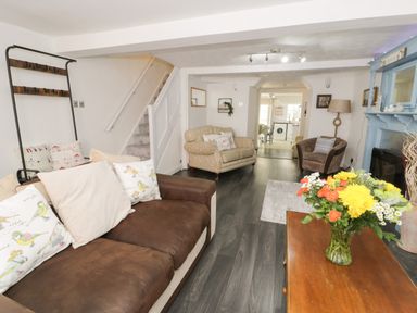 A living room with sofas, a wooden coffee table with flowers, and a blue fireplace at Penrallt in Cemaes Bay
