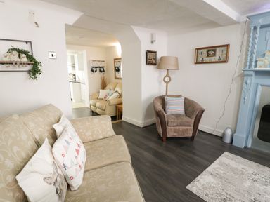 A living room with beige and brown armchairs a blue fireplace and a lamp at Penrallt in Cemaes Bay