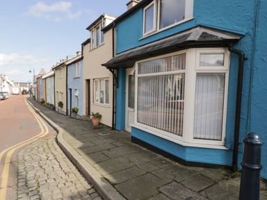 A street with colorful houses and a blue house with a bay window at Penrallt in Cemaes Bay