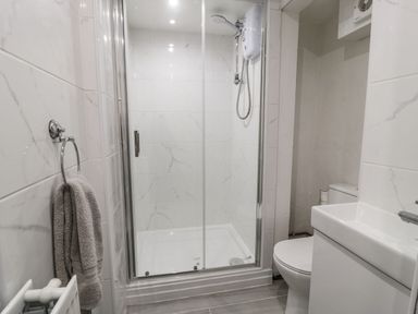 A bathroom with a shower enclosure toilet sink and towel at Penrallt in Cemaes Bay