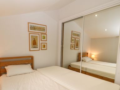 A bedroom with a wooden bed beside a mirrored wardrobe and framed pictures on the wall at The Moorings in Porthmadog