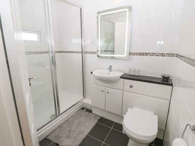 A bathroom with a shower enclosure sink toilet and a mirror above the sink at The Moorings in Porthmadog