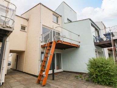 An outdoor area with balconies and stairs on a two-story building with a patio and plants at The Moorings in Porthmadog