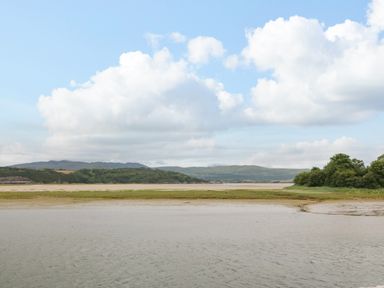 A coastal landscape with water grassy areas hills and a partly cloudy sky at The Moorings in Porthmadog