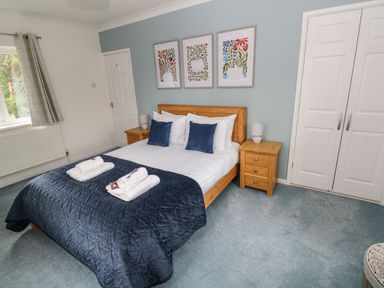 A bedroom with a double bed with blue cushions blue quilt and wooden bedside tables at Mews Cottage in Laugharne