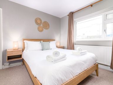 A bedroom with a wooden bed with white bedding and towels on it bedside tables with lamps and wall decorations at The View in Whitby