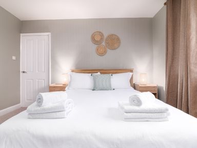 A bedroom with a double bed white linens bedside tables lamps and decorative wall hangings at The View in Whitby