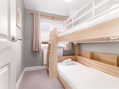 A bedroom with wooden bunk beds a window with curtains and a towel on the lower bed at The View in Whitby
