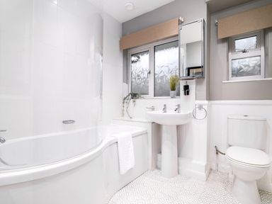 A bathroom with a bathtub, pedestal sink, toilet, frosted windows, and patterned floor tiles at The View in Whitby