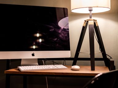 A desk with an iMac computer keyboard mouse and a tripod lamp at The View in Whitby
