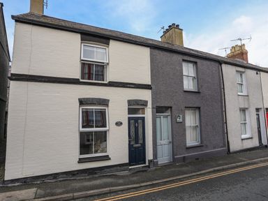 A street view of terraced houses with different colored facades and doors at Amelie Cottage in Beaumaris Anglesey
